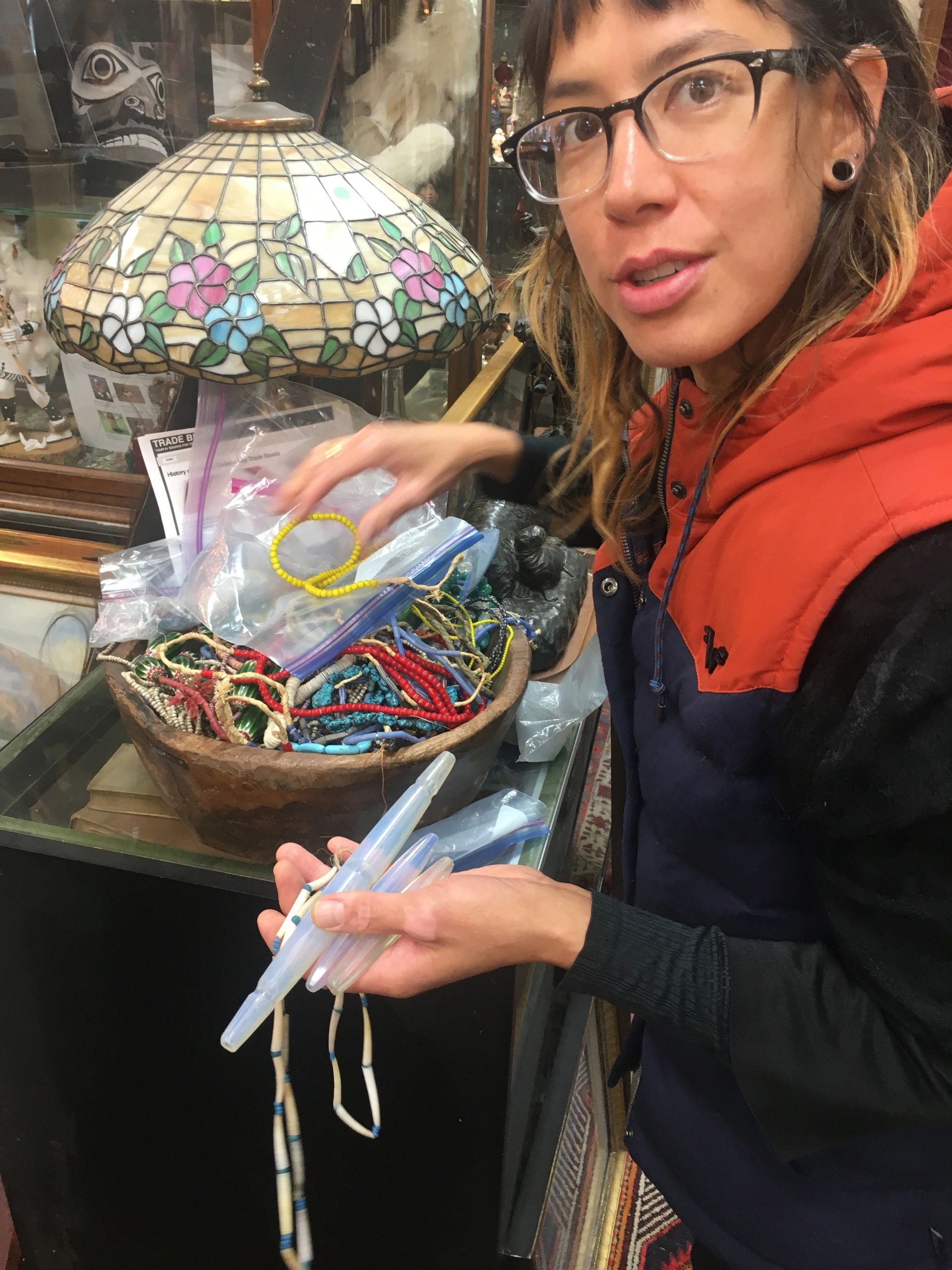 Chrissy at an antique dealer, holding a handful of trade beads over a bowl of strands.